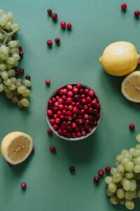 A balanced mix of berries, grapes, and lemons on a green background for healthy eating.